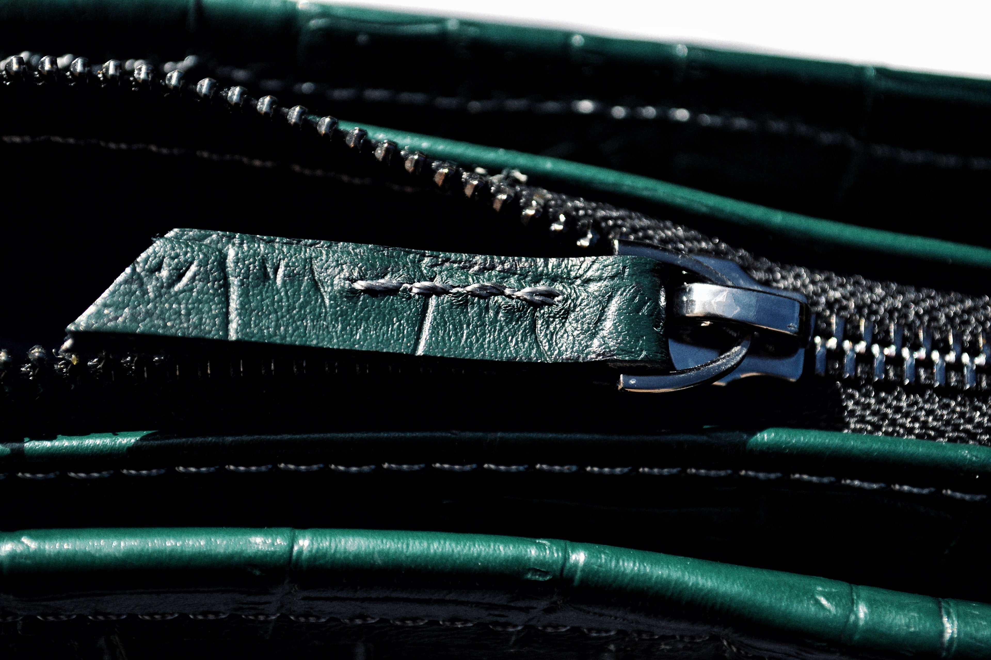 Close-up of a green leather wallet with a zipper