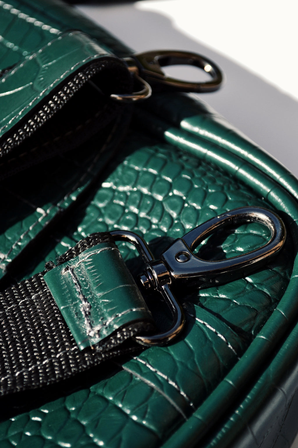 Close-up of a green textured handbag with a black strap and clasp.